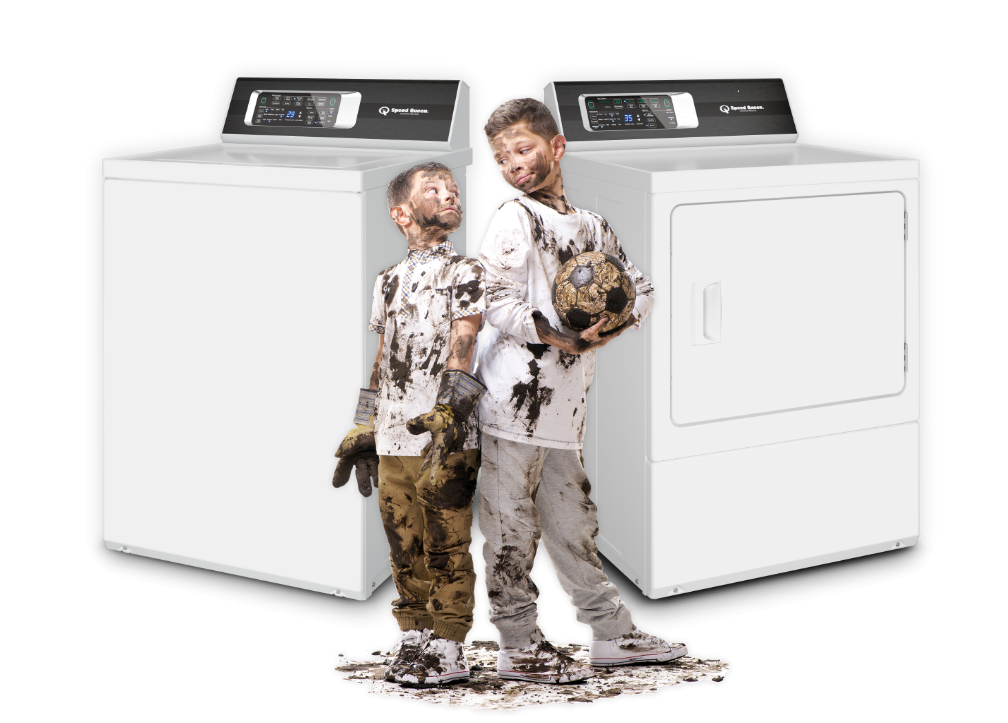 two boys in dirty soccer clothes in front of washer and dryer